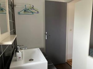 a bathroom with a white sink and a door at Chambre chez Armelle in Avoine +8 photos