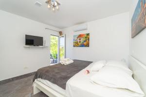 een witte slaapkamer met een bed en een televisie bij House Terra Madre in Gruda