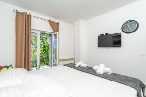 een witte slaapkamer met een bed en een klok aan de muur bij House Terra Madre in Gruda +68 foto's