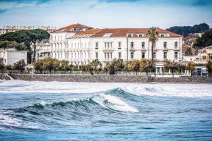 a surfer is riding a wave in the ocean at Grand Hotel Des Sablettes Plage, Curio Collection By Hilton in La Seyne-sur-Mer