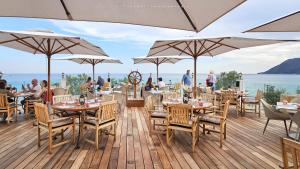 a restaurant with tables and umbrellas on a deck at Grand Hotel Des Sablettes Plage, Curio Collection By Hilton in La Seyne-sur-Mer