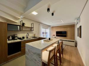 a kitchen with a counter and some chairs in it at Incrível Loft 235 1 Suíte Centro by Achei in Canela