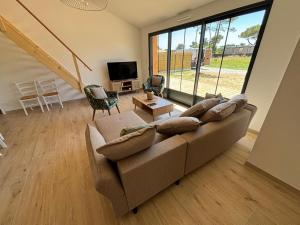 a living room with a couch and a large window at Maison du Bois, pinède et océan in Saint-Jean-de-Monts