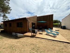 a deck with chairs and a table and an umbrella at Maison du Bois, pinède et océan in Saint-Jean-de-Monts
