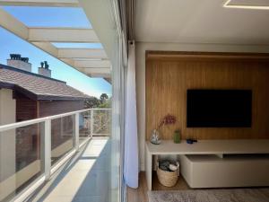 a balcony with a flat screen tv on a building at Incrível Loft 235 1 Suíte Centro by Achei in Canela