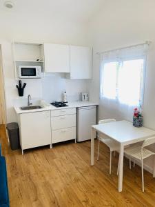 una cucina con armadi bianchi, tavolo e lavandino di Charmante maisonnette neuve proche Thalasso a Sainte-Marie-de-Ré Altre 4 foto