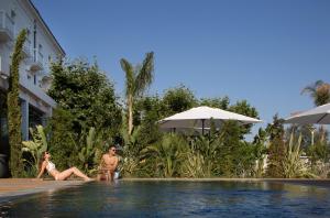two people sitting in a swimming pool at a resort at Grand Hotel Des Sablettes Plage, Curio Collection By Hilton in La Seyne-sur-Mer