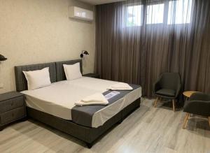 a bedroom with a bed and two chairs and a window at Българе in Vratsa