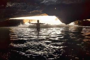 a person standing in the water in a cave at Paraíso Particular- Casa na Praia De Camurupim- Pedra Oca in Nísia Floresta