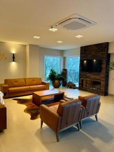 a living room with couches and a tv and a fireplace at Sensacional Flat Serra Class - vista do Pôr do Sol in Canela +12 photos