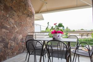 a table and chairs on a patio with a stone wall at Chasapis Luxury Apartments&Studios in Vourvourou