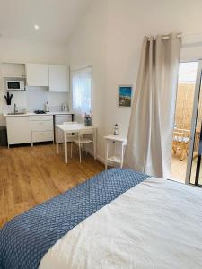 una camera da letto con un letto e una cucina con un tavolo di Charmante maisonnette neuve proche Thalasso a Sainte-Marie-de-Ré