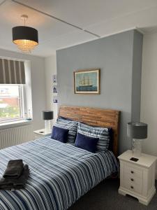 a bedroom with a bed with blue and white stripes at On The Harbour - unrivalled views of Amble's harbour and estuary in Amble