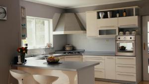 a kitchen with white cabinets and a island with chairs at Villa Rita in Županja