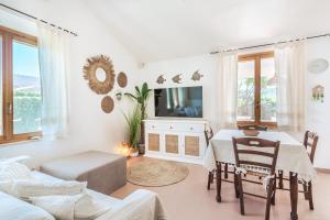 sala de estar blanca con mesa y sofá en Villa Vinghi - Villasimius, en Villasimius