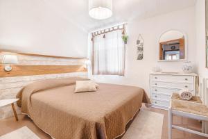 Un dormitorio con una cama, una cómoda y un espejo. en Villa Vinghi - Villasimius, en Villasimius