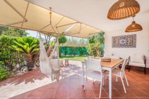 Un patio con mesa y sillas y una hamaca. en Villa Vinghi - Villasimius, en Villasimius 37 fotos más