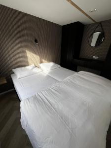 a large white bed in a bedroom with a wall at Stekkie 49 in Schagen +8 photos