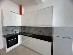 a white kitchen with a sink and a refrigerator at Ameti - Ground Floor Comfort Suites - Spacious & Modern in Orikum