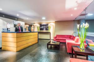 a man standing at a bar in a hotel lobby at Travelers Obelisco Apartamentos in Bogotá