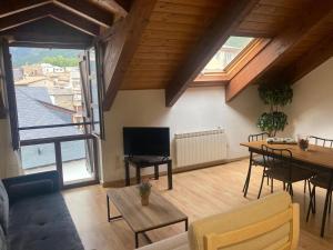 a living room with a television and a table and chairs at AT Refugio del Pirineo in Biescas
