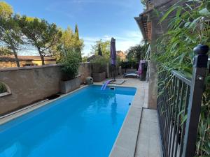 ein großer blauer Pool neben einem Zaun in der Unterkunft Logement indépendant Au Bonheur cuisine piscine clim proche centre village #dentelles Montmirrail in Beaumes-de-Venise