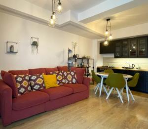 a living room with a red couch and a kitchen at Forest Oasis Studio - free Netflix and Disney Plus in Predeal