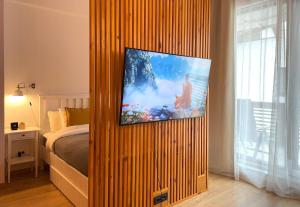 a bedroom with a television on a wooden wall at Forest Oasis Studio - free Netflix and Disney Plus in Predeal