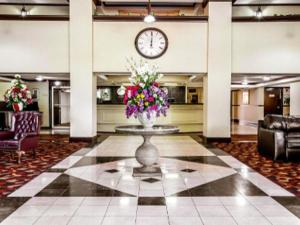 a lobby with a clock on the wall and a vase of flowers at Ramada by Wyndham Birmingham Airport in Birmingham