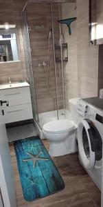 a bathroom with a toilet and a shower with a starfish rug at Garsoniera Saturn in Saturn