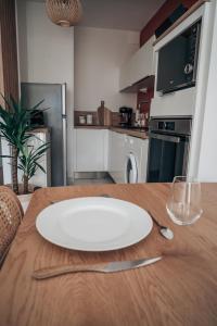 eine weiße Platte auf einem Holztisch in der Küche in der Unterkunft Le Terra Cholet - T2 Centre - Terrasse - Parking - 25 min Puy duFou in Cholet + 20 Fotos