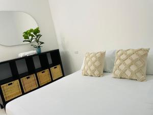 a white bed with two pillows and a plant on it at Hostal 1545 in Ríohacha +6 photos
