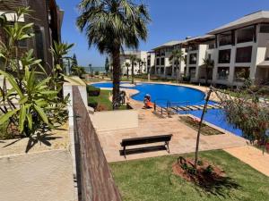 een persoon op een bankje naast een zwembad bij Front Beach - Bahia Golf Beach in Bouznika