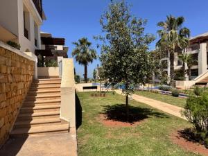 een gebouw met trappen en een boom in een tuin bij Front Beach - Bahia Golf Beach in Bouznika