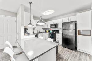a kitchen with white cabinets and a black refrigerator at Spacious 2BR King Suites w Pool, Gym, Laundry - Close to Downtown in Austin +29 photos