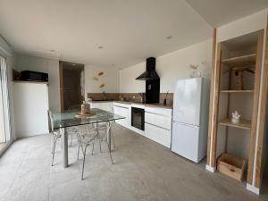 a kitchen with a glass table and a refrigerator at Le gîte des cigales du Devès in Salavas