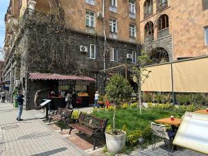 a group of benches and tables in front of a building at Your Cascade Home: In Yerevan Heart in Yerevan