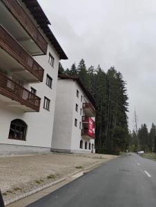 an empty road next to a white building at Forest Oasis Studio - free Netflix and Disney Plus in Predeal