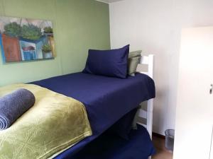 a small bedroom with a bed with blue sheets at Wellust Cottage at Ngweni Private Game Farm in Hluhluwe