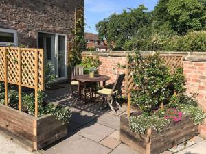 a patio with a table and chairs in a garden at The Barn in Tollerton
