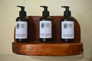 three bottles of soap sitting on a wooden shelf at Casa de Vista Alta in Mindo