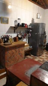 a kitchen with a stainless steel refrigerator and a table at Casa SERRA DA BALANÇA - PÉROLA DA MANTIQUEIRA in Gonçalves