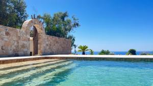 una piscina junto a una pared de piedra y el océano en Auberge Ferayola, en Galeria