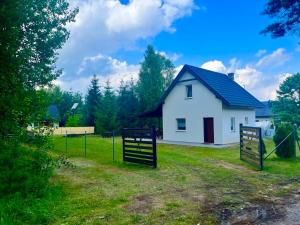 a white house with two gates in the grass at Letnia Ostoja Wieprz nad Jeziorakiem in Zalewo +4 photos