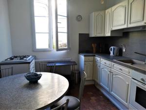 a kitchen with white cabinets and a table in it at Vue sur Chateau et Loire in Saumur