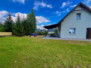 a white house with a green yard with a picnic table at Letnia Ostoja Wieprz nad Jeziorakiem in Zalewo