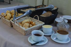 a table with baskets of bread and cups of coffee at HANNA Praia Hotel - Florianópolis in Florianópolis