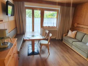 Una pequeña sala de estar con una mesa y un sofá. en Haus Elisabeth Sporer, en Schwendau 7 fotos más