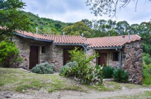 a stone house with a red roof at Cabañas Las Perdices de Candonga in Agua de Oro