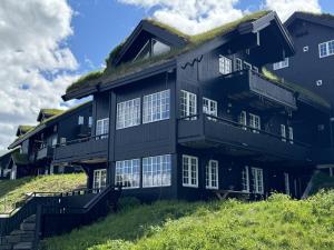 a black house with a grass roof at Cozy Ski-In Ski-Out Apartment on Geilo, Stunning Views! in Geilo